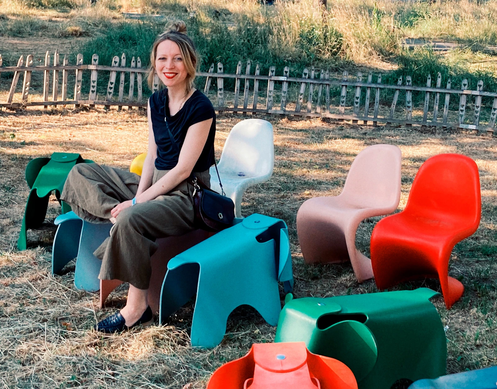 Cécile Hoggenmüller, founder of CÉHO studio, seated among colourful chairs