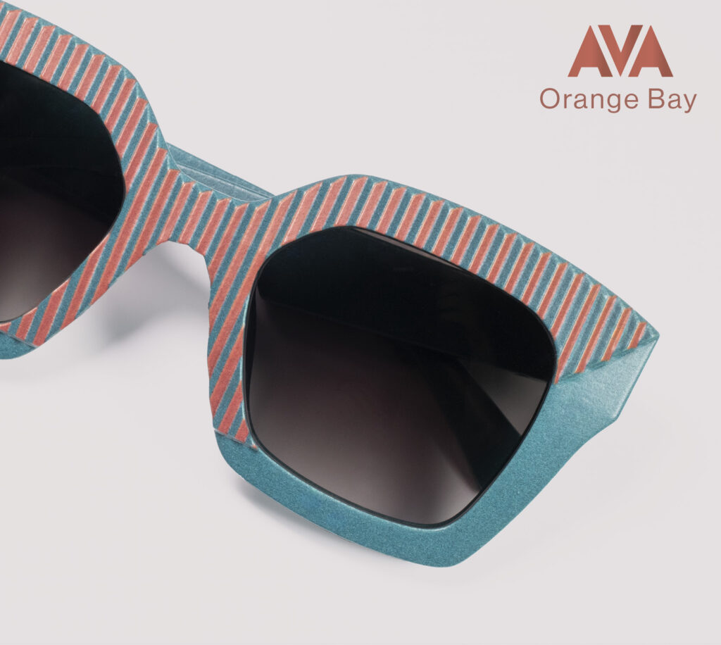 Close-up of AVA Orange Bay sunglasses by CEHO Studio, featuring a bold striped frame in teal and coral with dark lenses.