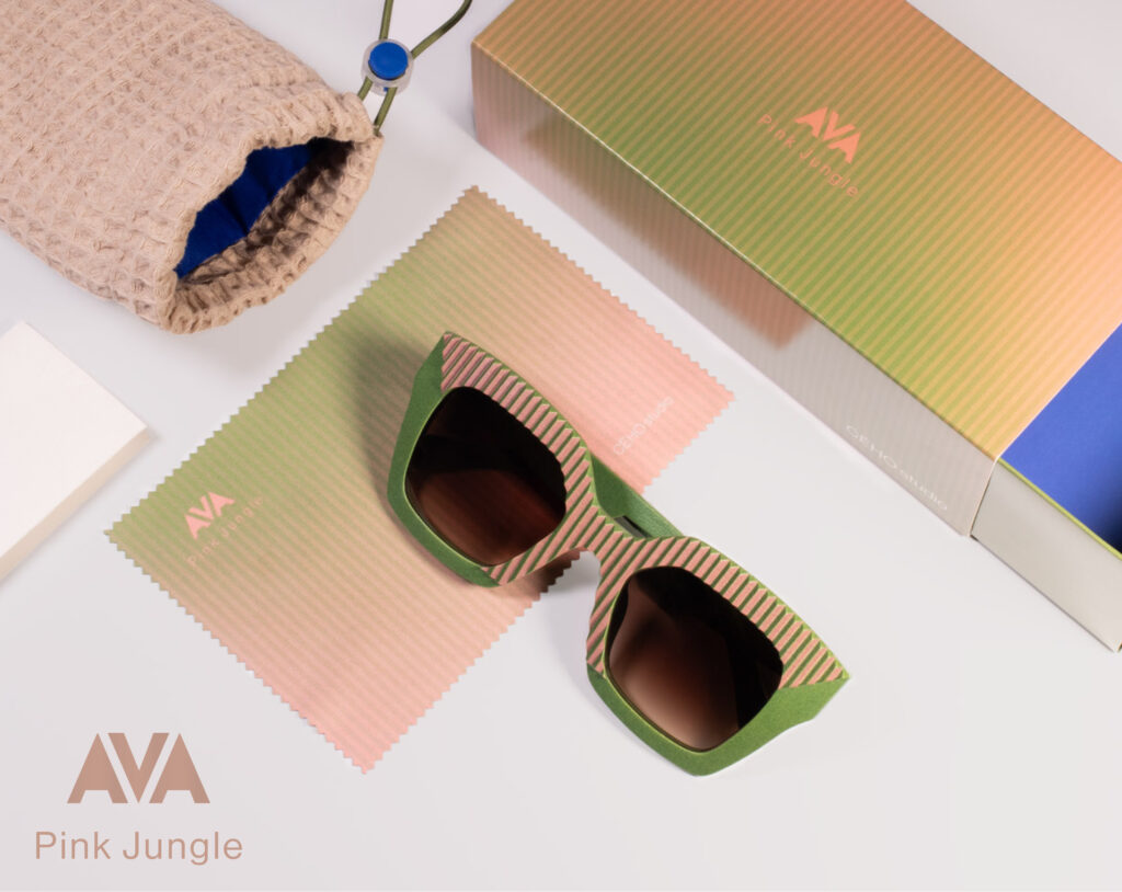 Flat lay of AVA Pink Jungle sunglasses by CEHO Studio with matching striped cleaning cloth, gradient packaging box, and soft protective pouch.